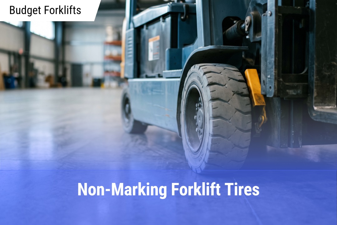 Close-up of a grey non-marking cushion tire on a steel-blue electric forklift turning on a glossy epoxy warehouse floor.