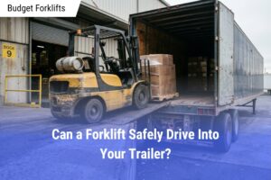 Yellow forklift driving up a metal ramp into a loaded dry van trailer at an industrial warehouse loading dock.